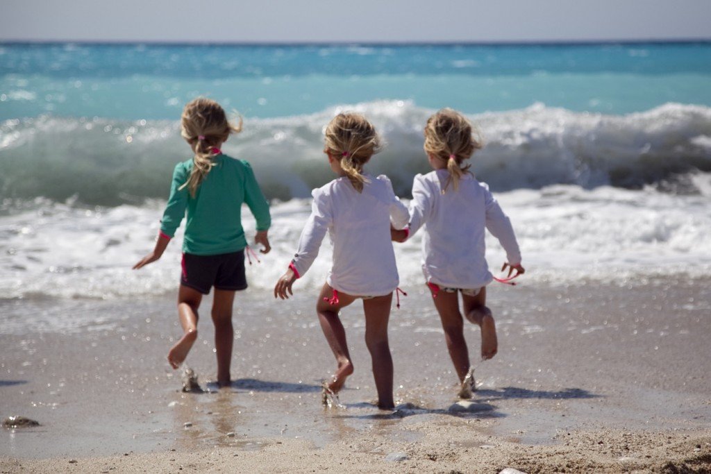Children playing on a beach in their swimming gear - one of the things you could pack in your beach ready beach bag