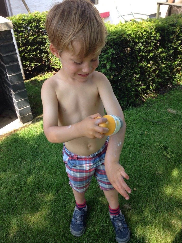 Child applying sunscreen independently using Solar Buddies