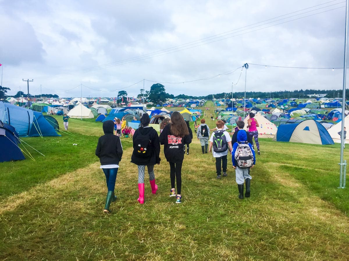 Kids at a festival walking through a field of tents